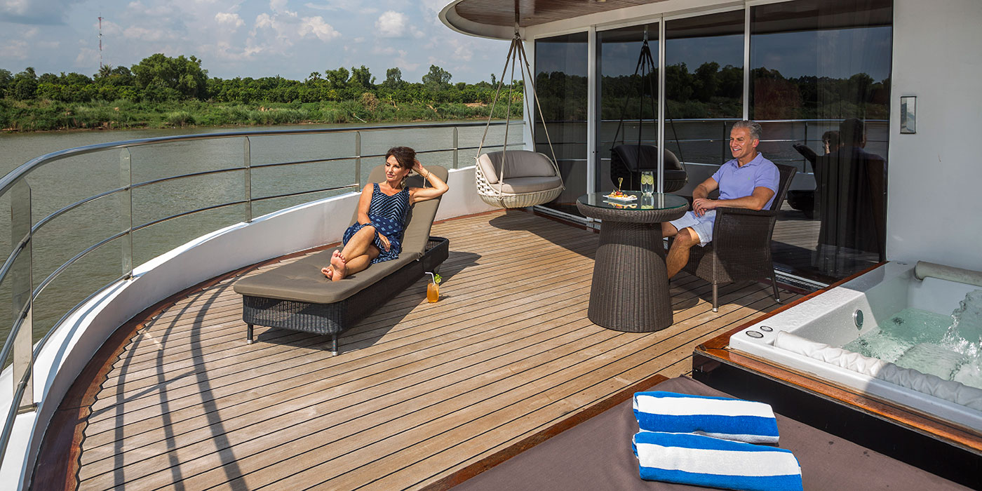 A man and woman relaxing on the outdoor terrace of the Royal Panorama Suite on the Scenic Spirit ship.