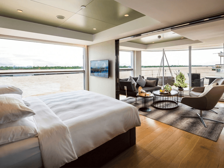 Bed and separate lounge area with floor-to-ceiling windows in the Royal Panorama Suite