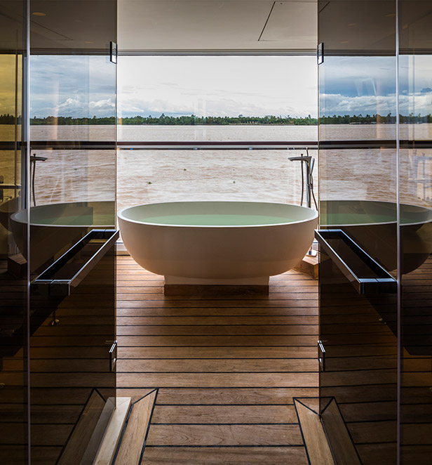 A white bath next to a floor-to-ceiling window with views of the Mekong River
