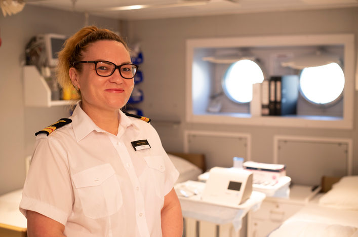 Nurse smiling with hospital beds in background