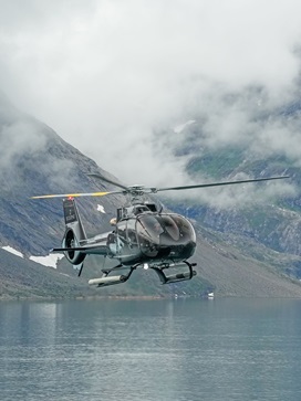 Helicopter flying in front of a mountain engulfed in clouds