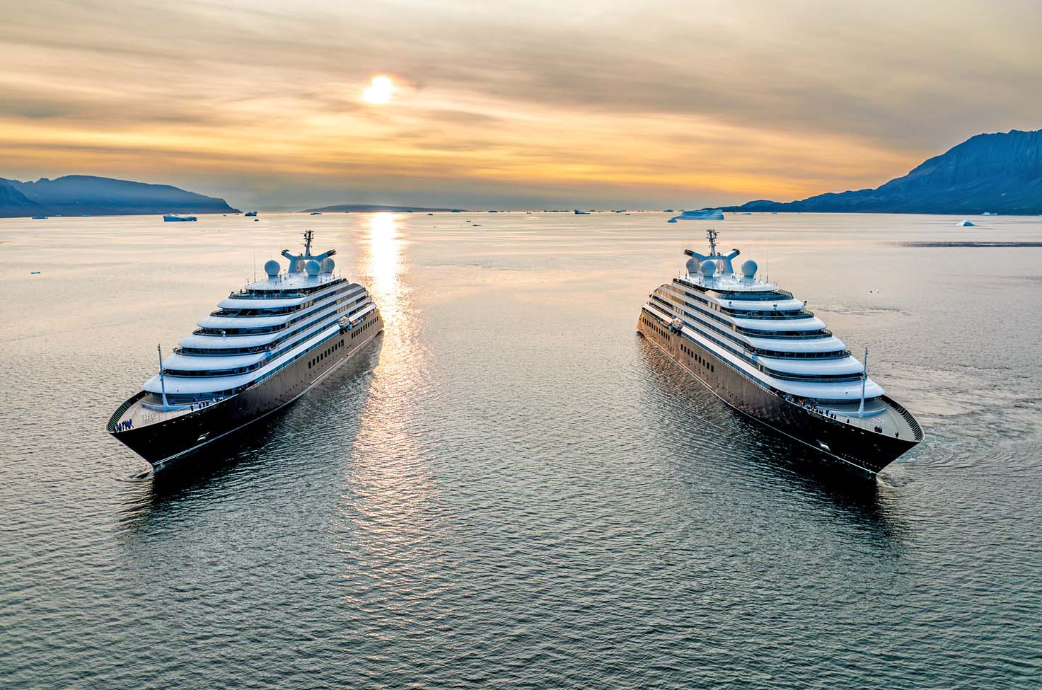 Two luxury yacht ships sailing side by side at sunset