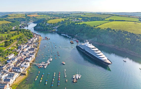 Scenic Eclipse ship sailing past a small town in Cornwall, United Kingdom