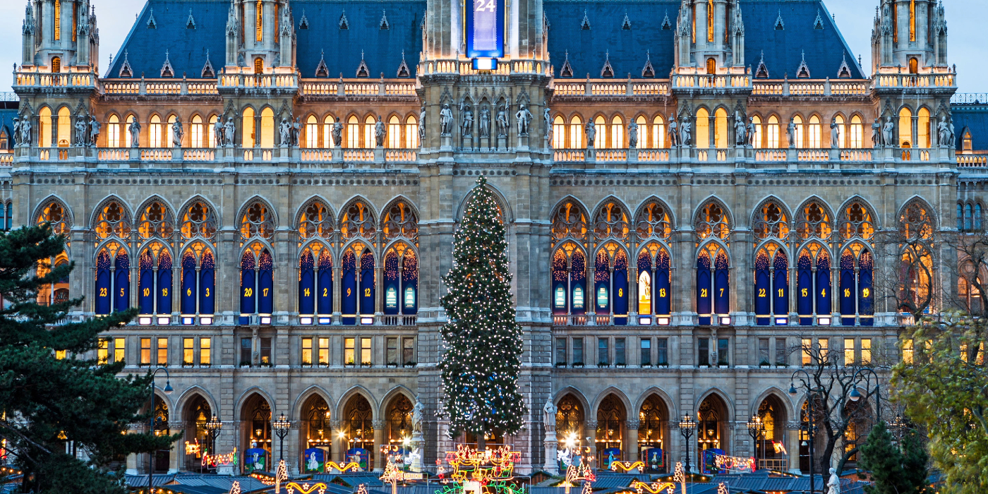 Christmas tree in front of Vienna's Parliament Building, adorned with colorful lights and ornaments.