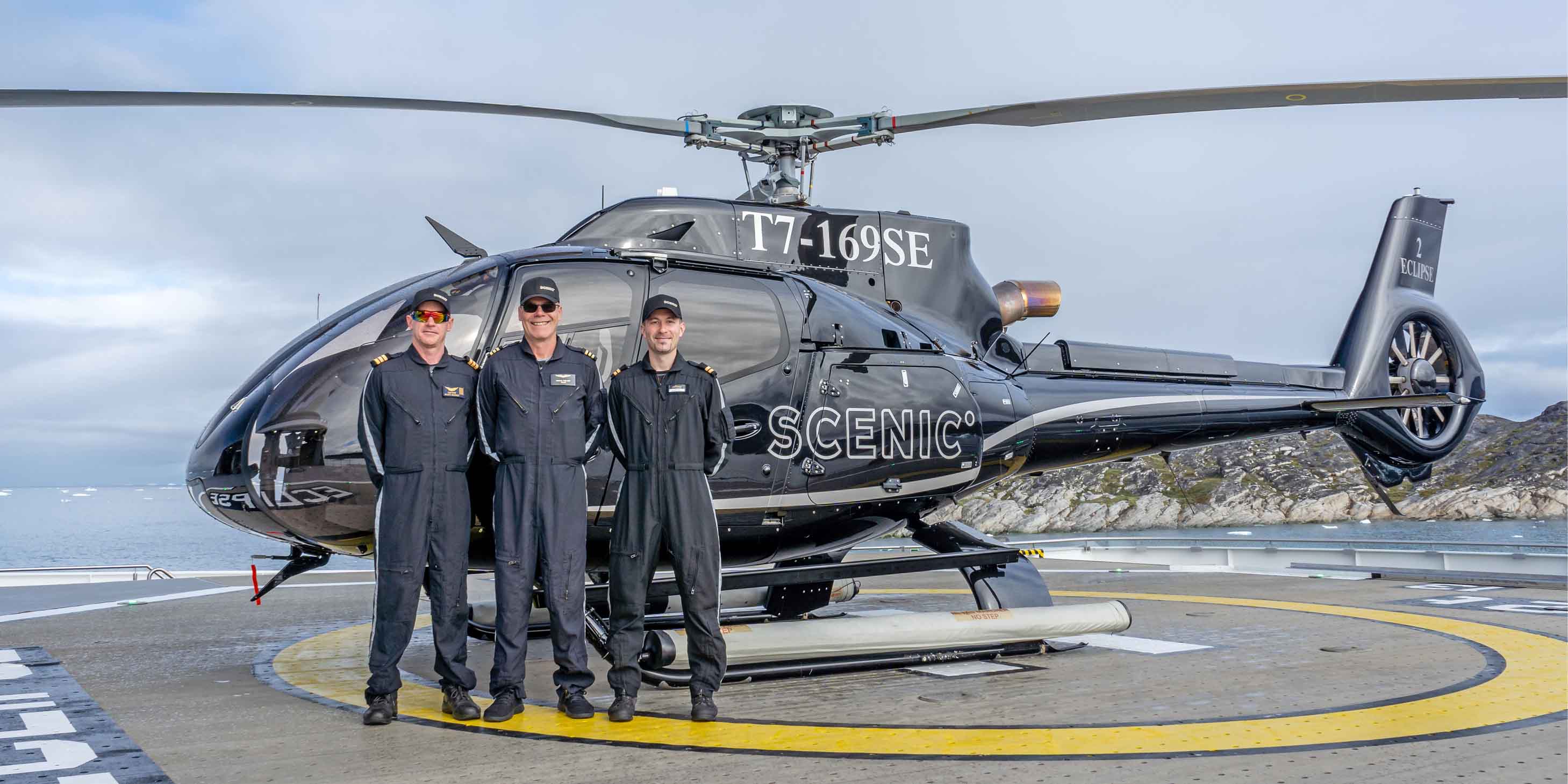 Helicopter crew standing in front of helicopter on landing pad